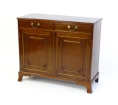 A mahogany cabinet with a moulded top above two short drawers and two panelled cupboard, the cabinet