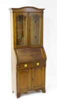 An early / mid 20thC glazed oak bureau, with an arched pediment above stained, leaded glass doors, a