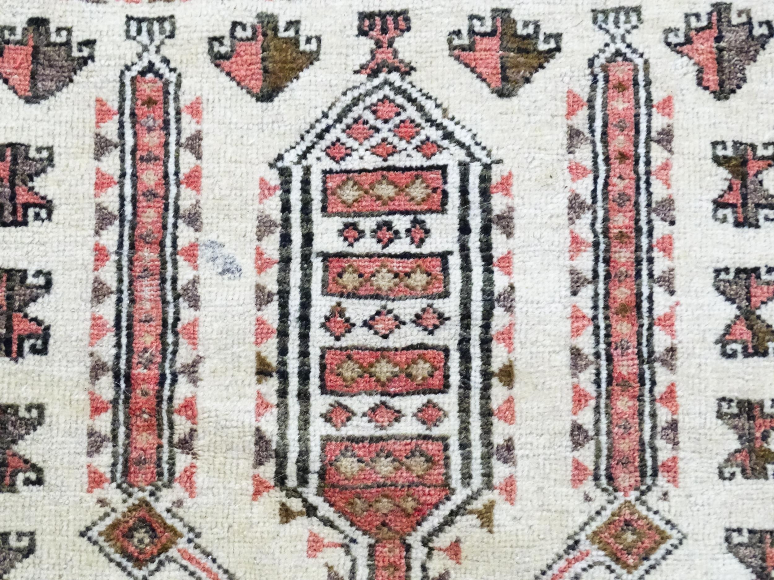 Carpet / Rug: A beige ground rug with repeated motifs worked in salmon pink, brown and beige, with - Image 7 of 9