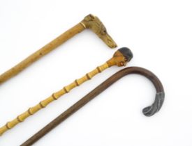 Three 20thC walking sticks / canes comprising one with a carved pommel formed as a folk art head,
