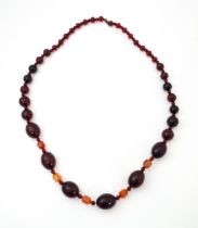A long bead necklace of graduated cherry amber coloured beads with facet bead detail . Approx 42"