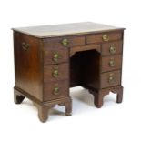 An early / mid 18thC oak kneehole desk with a moulded top above two short drawers and two banks of