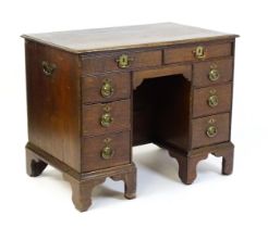 An early / mid 18thC oak kneehole desk with a moulded top above two short drawers and two banks of