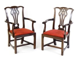 A pair of Chippendale style mahogany elbow chairs with a drop in seat raised on chamfered legs