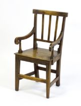 A Georgian child's chair with reeded back slats, scrolled arms and raised on tapering legs united by