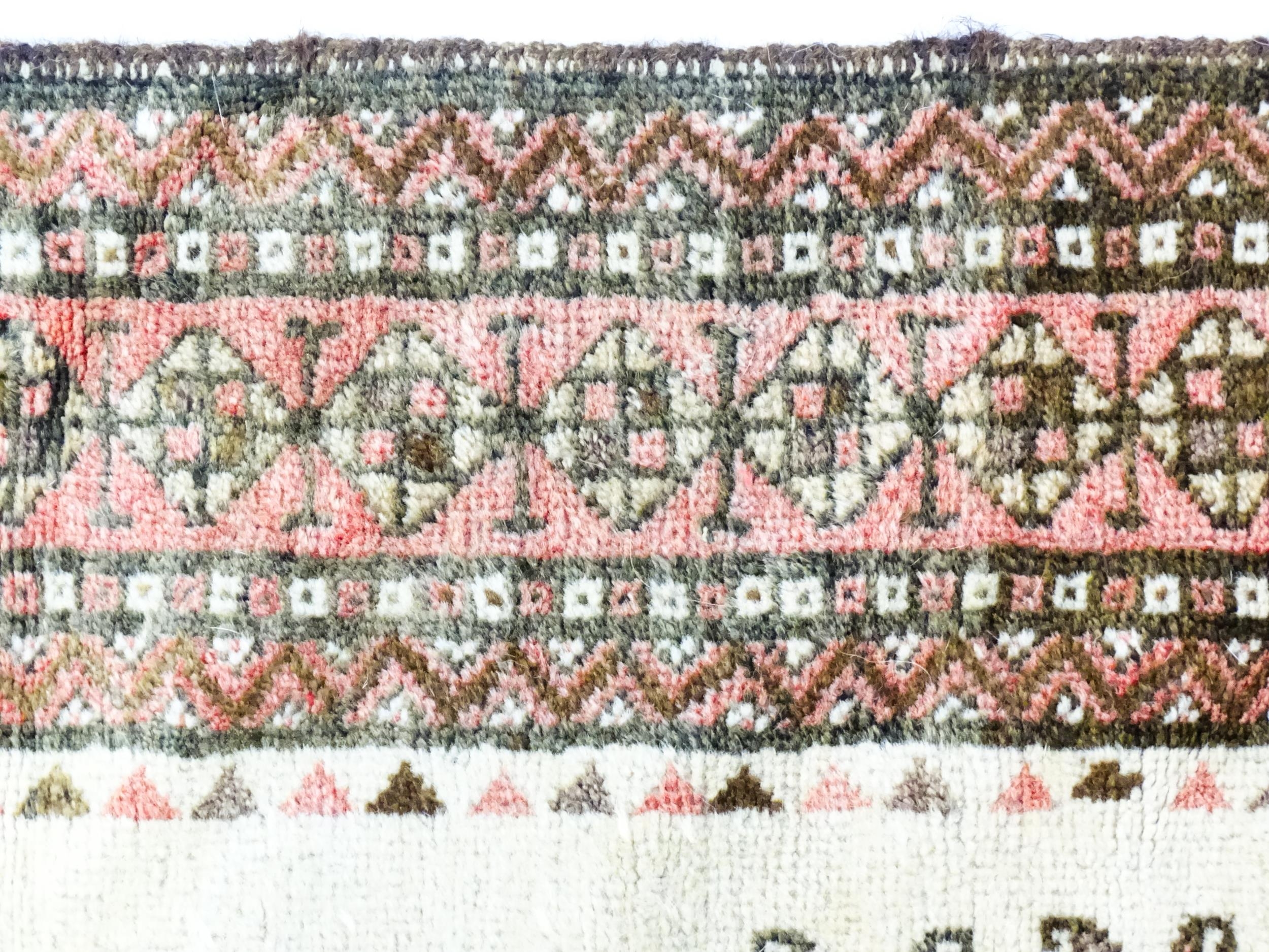 Carpet / Rug: A beige ground rug with repeated motifs worked in salmon pink, brown and beige, with - Image 4 of 9