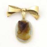 A cameo brooch, the oval cameo suspended from a 9ct gold bow formed corsage brooch hallmarked London