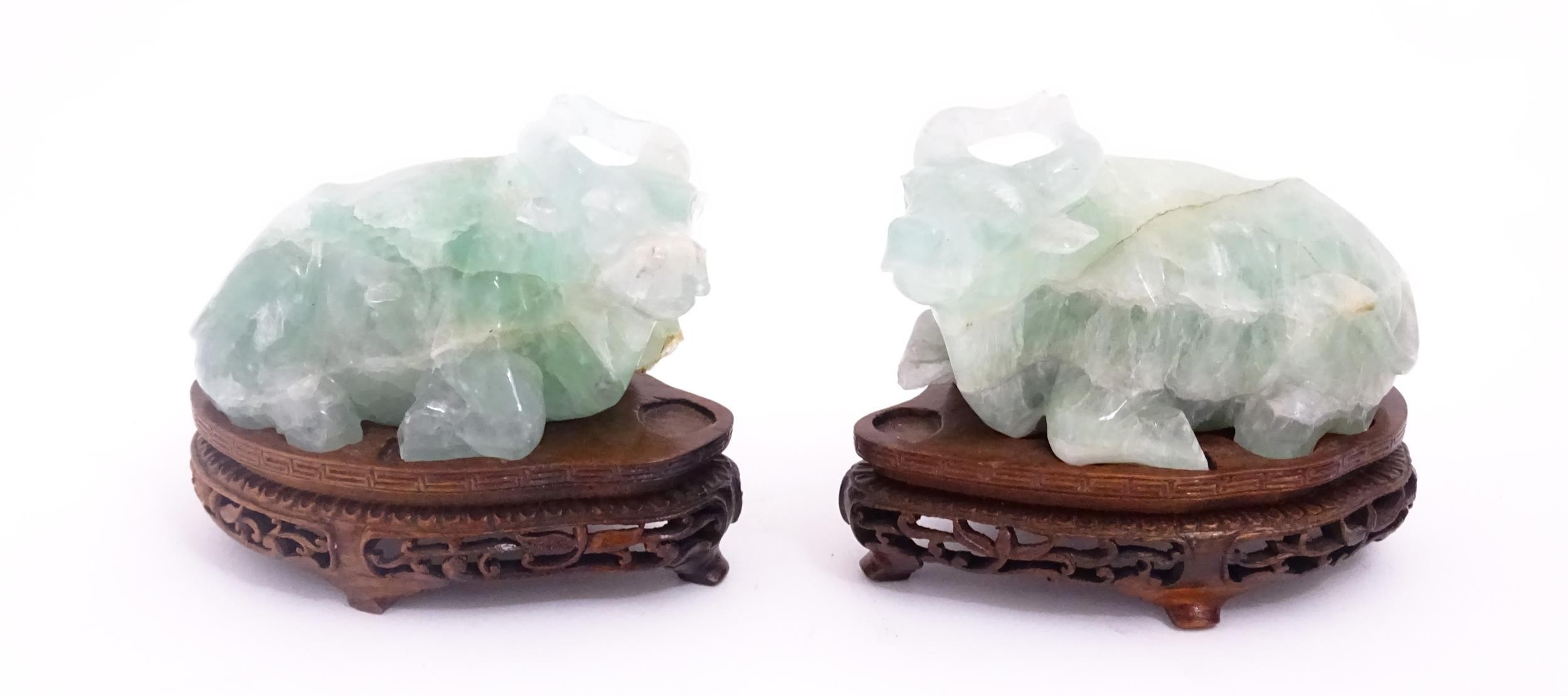 Two Chinese carved green fluorite models of recumbent buffalo, on wooden stands. Approx. 5" wide (2)
