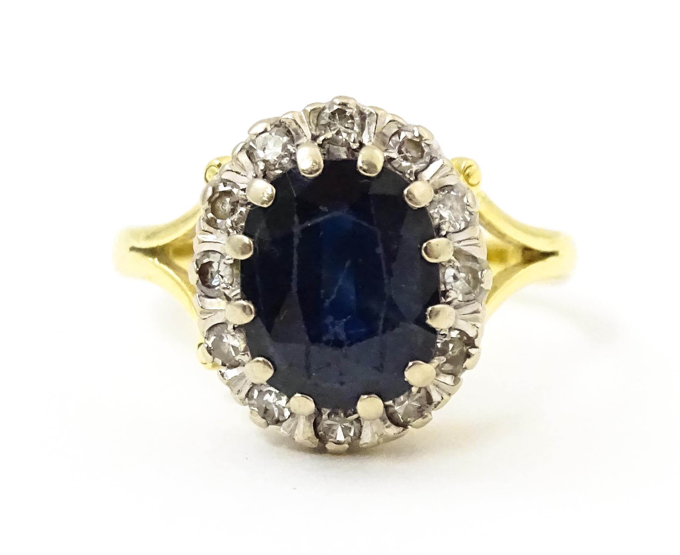 An 18ct gold ring set with central sapphire bordered by diamonds. Ring size approx. L 1/2 Please