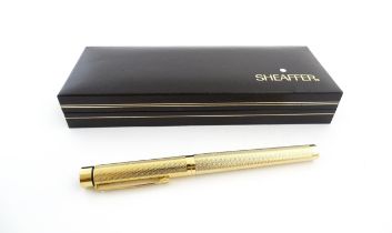 A cased Sheaffer 'Targa 1009' fountain pen with gold plated chequered barrel and cap, 14ct gold nib,