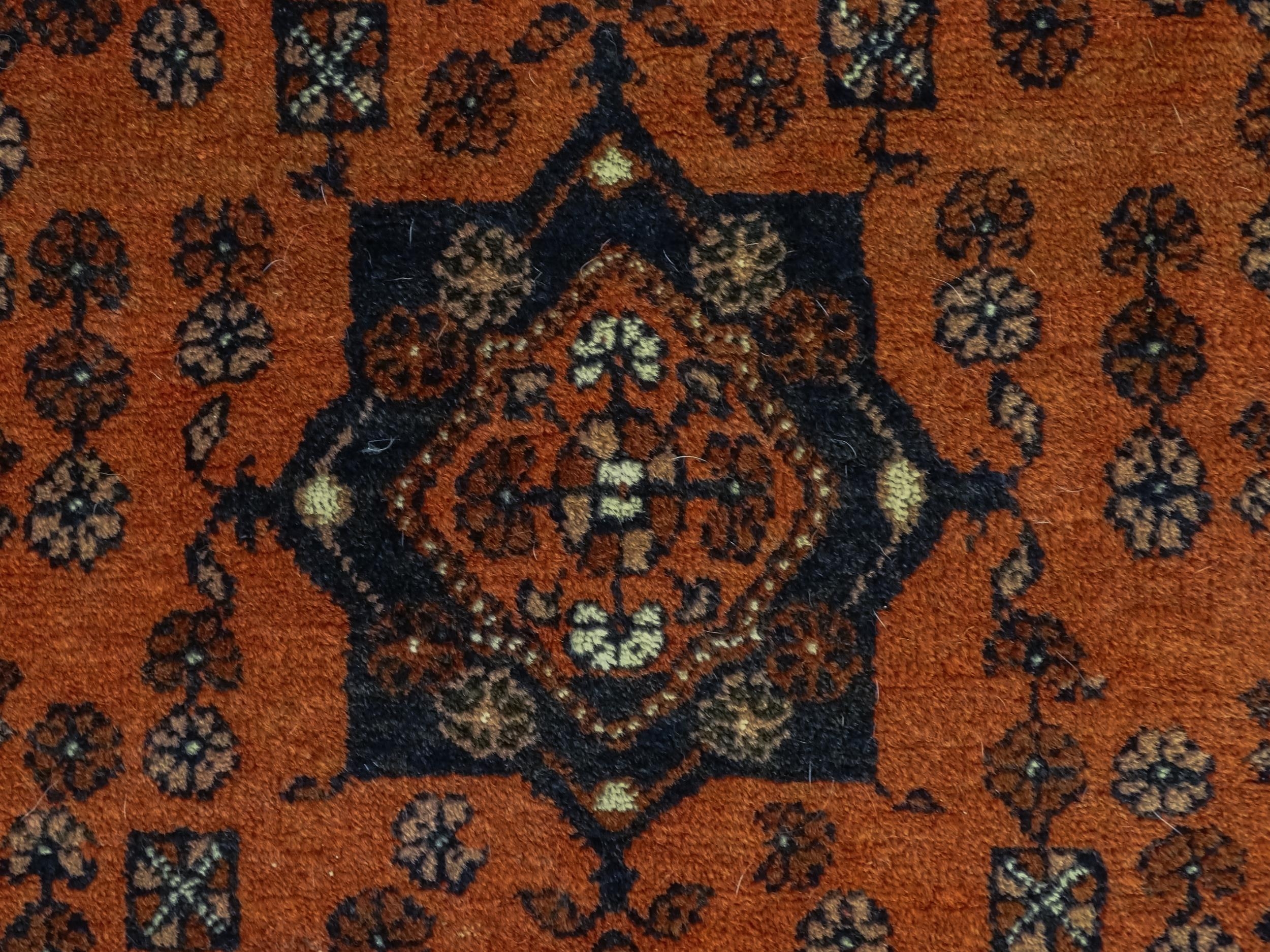 Carpet / Rug: A red ground rug decorated with floral and foliate detail, further repeated to - Image 6 of 8