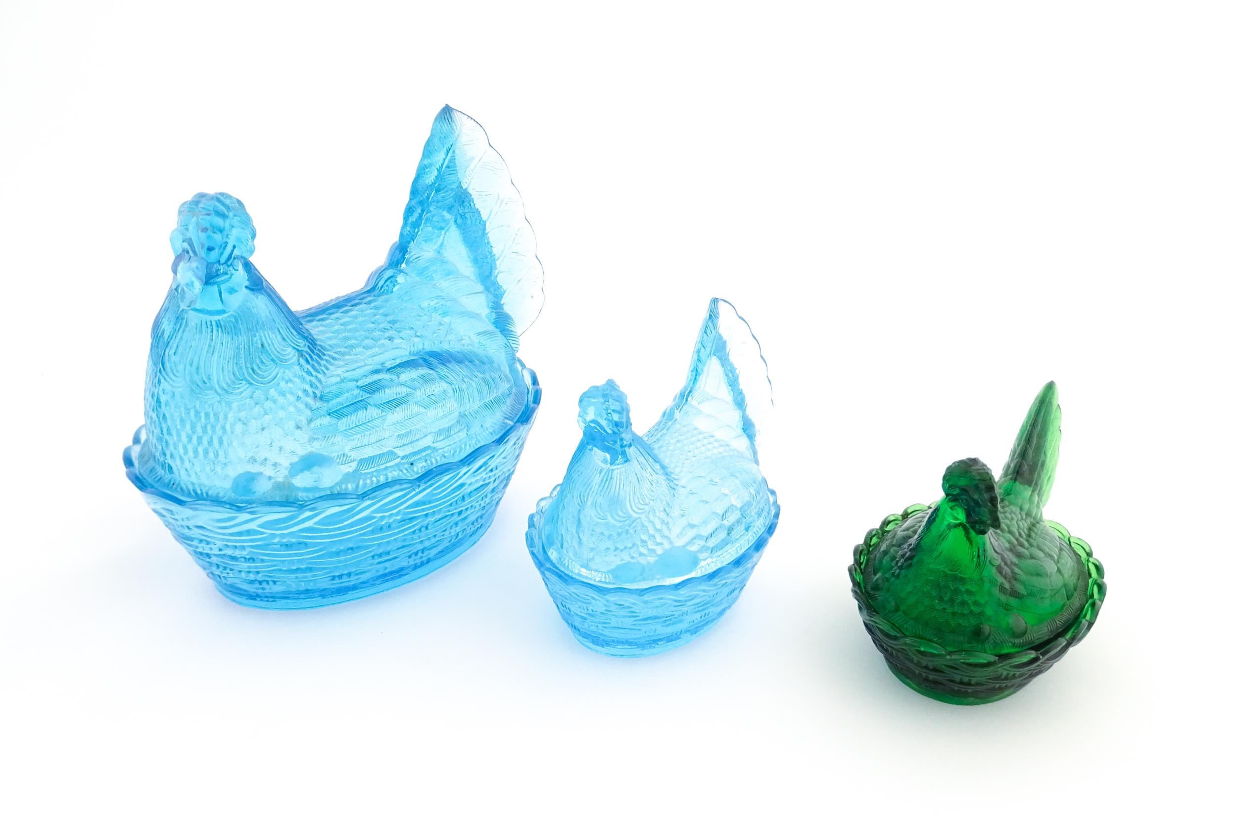 Three 20thC glass hen on nest egg containers, comprising two blue and one green. Largest approx. 8