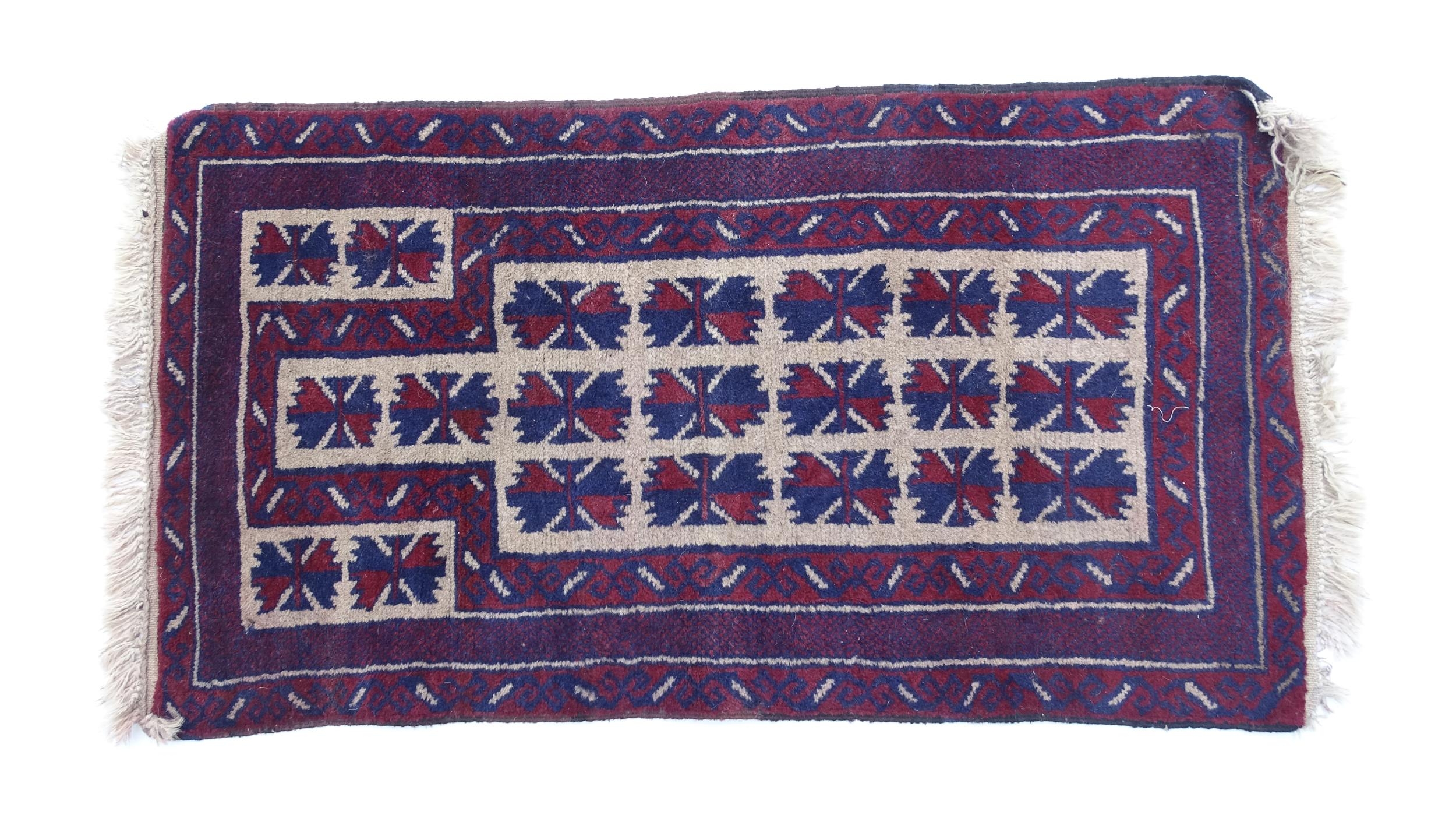 Carpet / Rug : A red, blue and cream ground rug with repeating geometric motifs. Approx. 55" x 29"