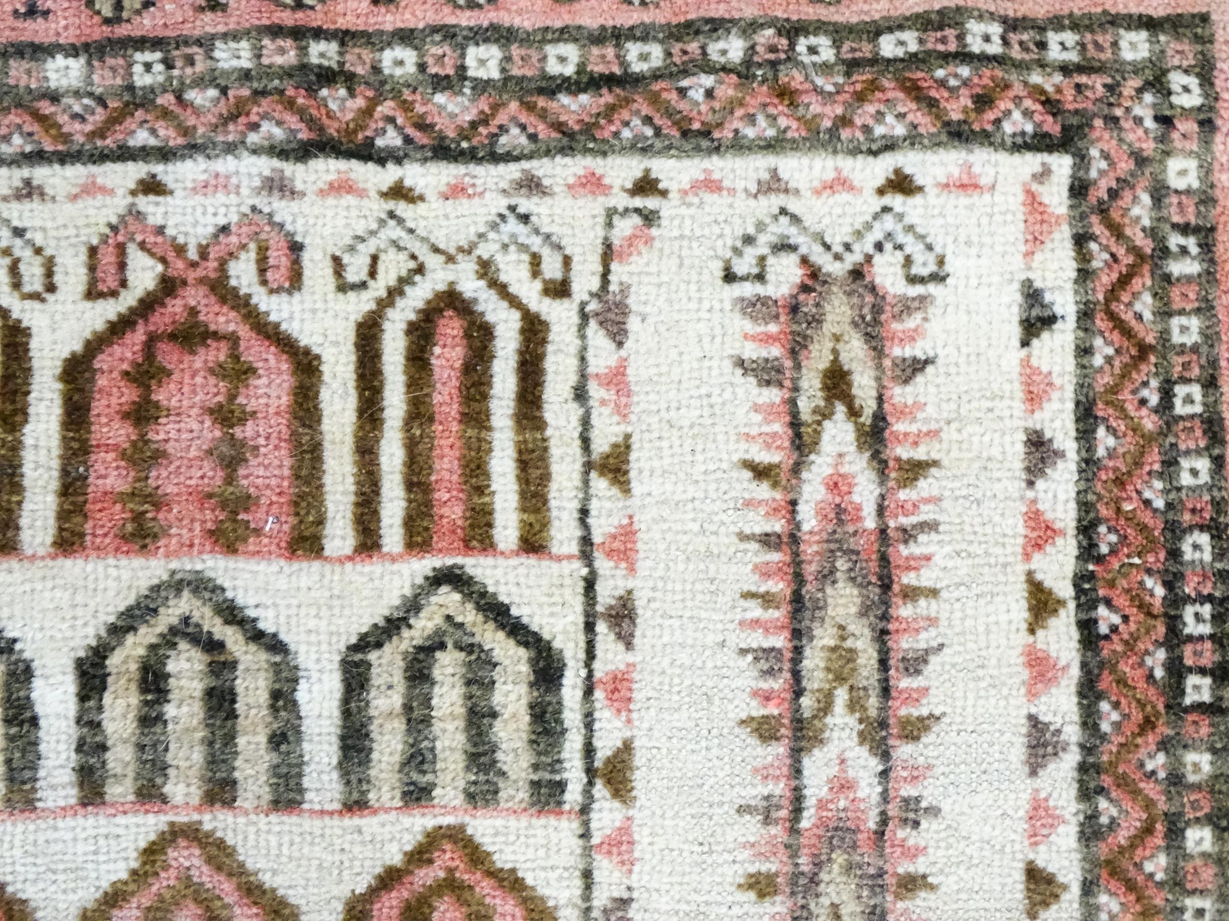 Carpet / Rug: A beige ground rug with repeated motifs worked in salmon pink, brown and beige, with - Image 5 of 9