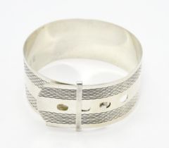 A silver bangle bracelet formed as a belt with engraved decoration. Marked Sterling Silver. Please