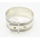 A silver bangle bracelet formed as a belt with engraved decoration. Marked Sterling Silver. Please