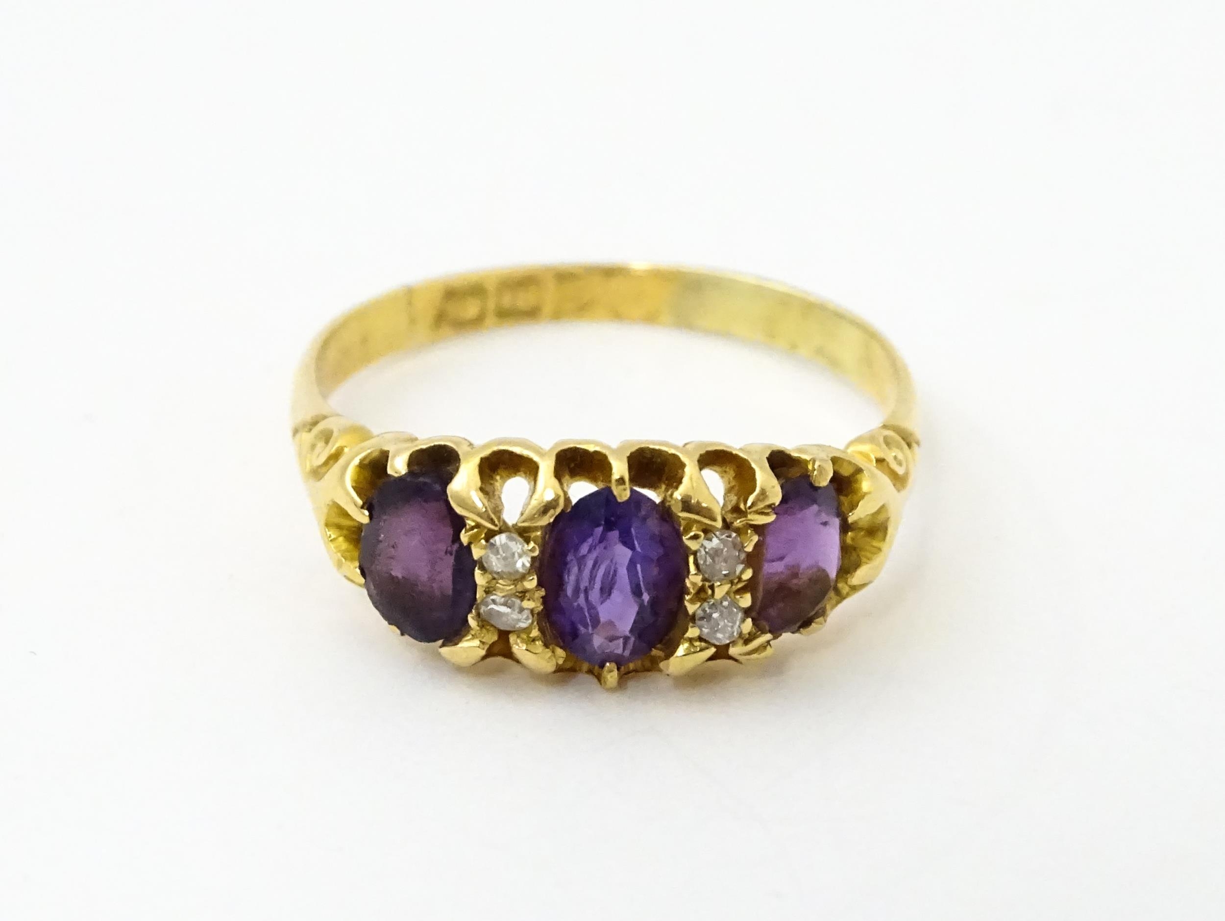An 18ct gold ring set three graduated amethyst and four diamonds. Ring size approx. Q Please