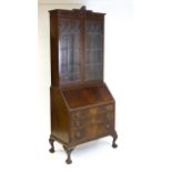 An early 20thC mahogany bureau bookcase with a carved cornice above two astragal glazed doors and