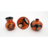 Three studio pottery items by Anita Harris to include two small bases and a dish, each with a red