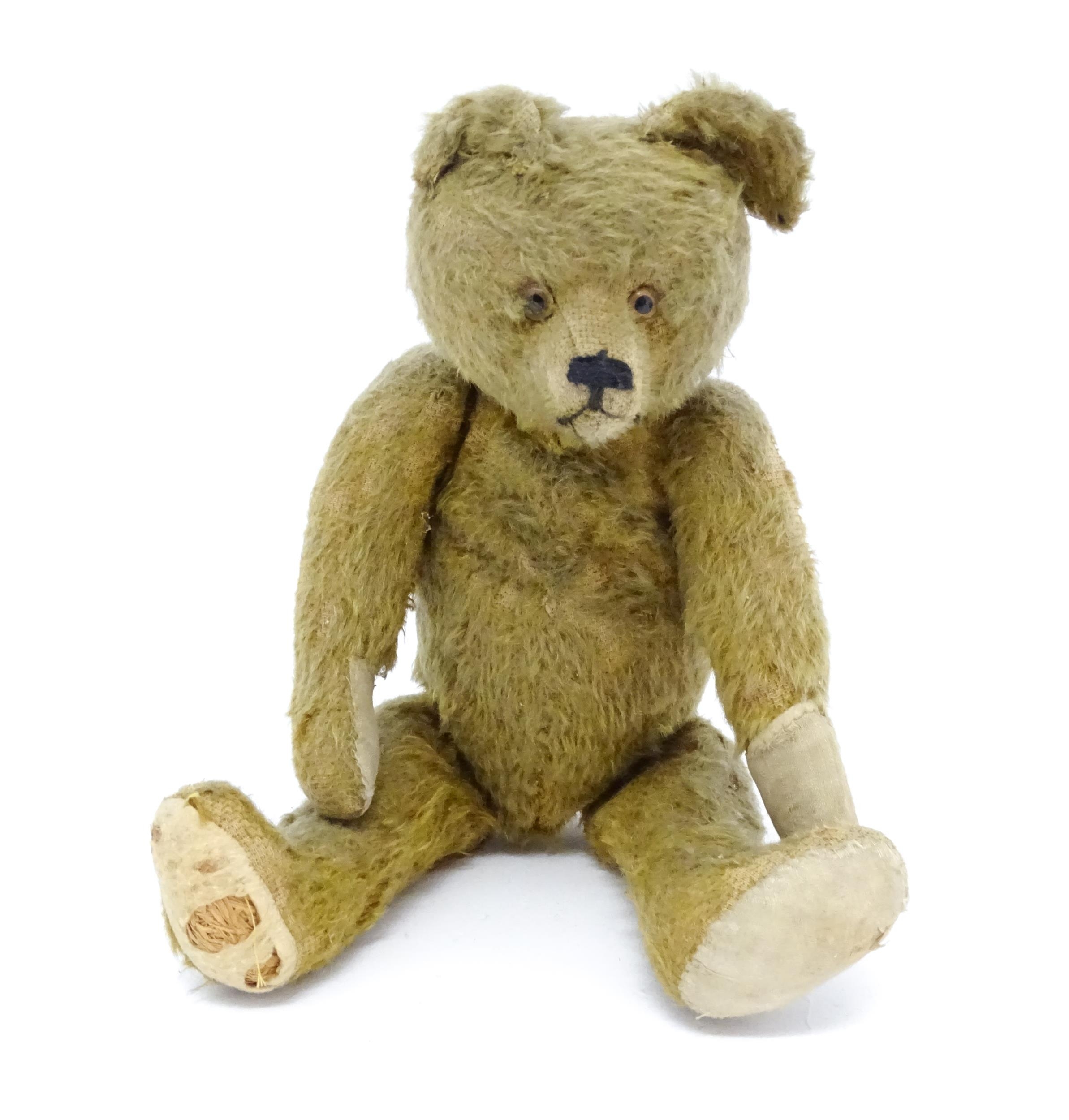 Toy: An early 20thC mohair straw filled teddy bear with proud nose, stitched mouth, hump back,