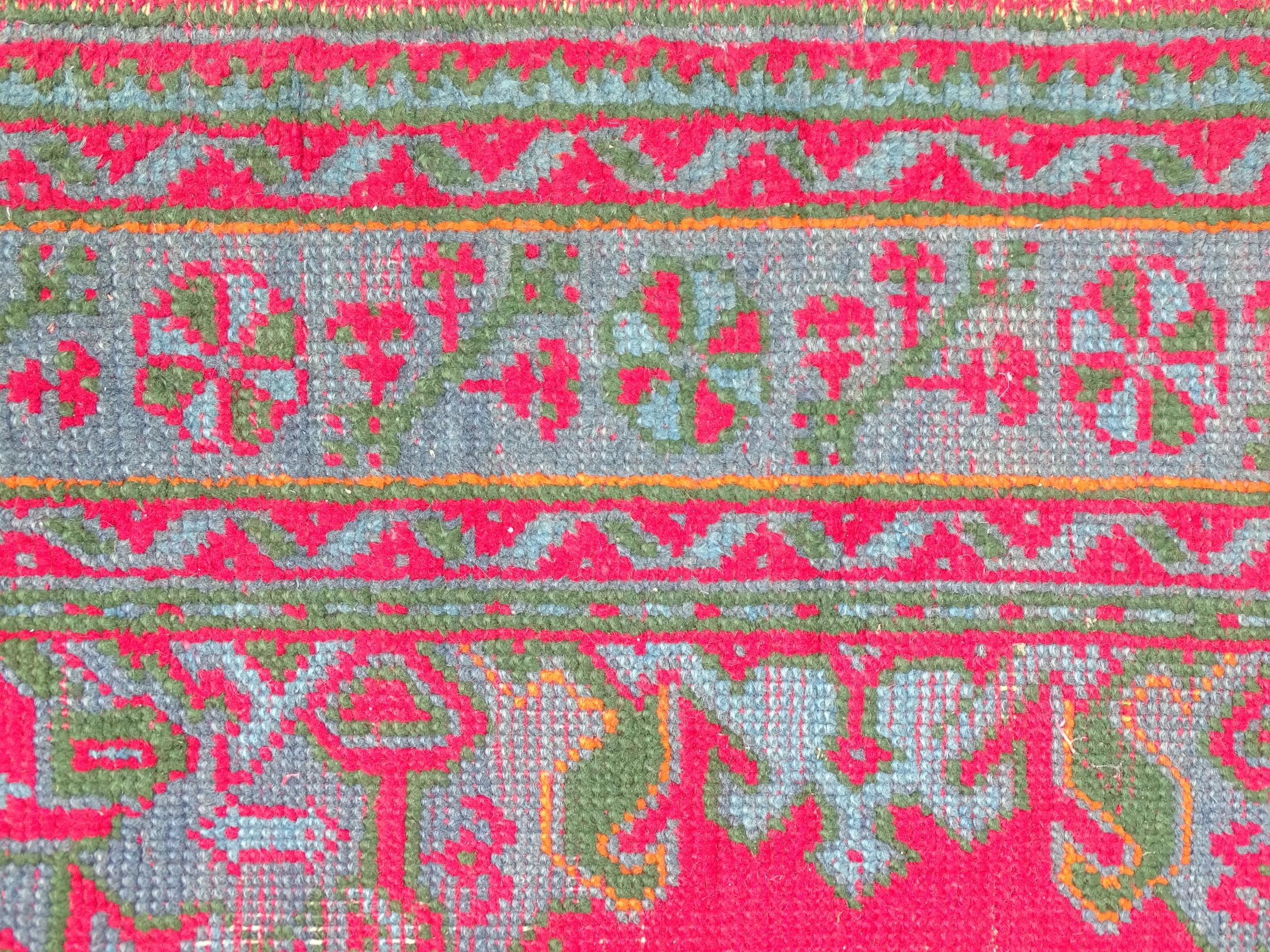 Carpet / Rug : A red ground rug decorated with floral, foliate and geometric detail worked in blue - Image 5 of 7