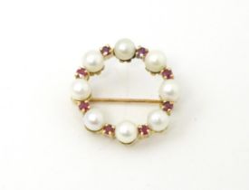 A 9ct gold pendant / brooch of circular set with pearls and round cut rubies. Approx 1" wide