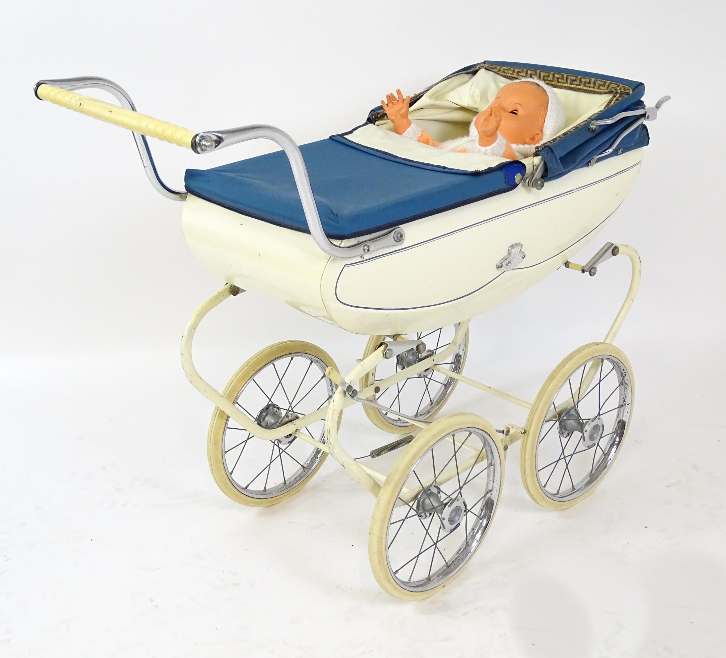 Toys: A 20thC Pedigree dolls pram with cream exterior and blue hood. Together with a plastic doll