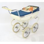 Toys: A 20thC Pedigree dolls pram with cream exterior and blue hood. Together with a plastic doll