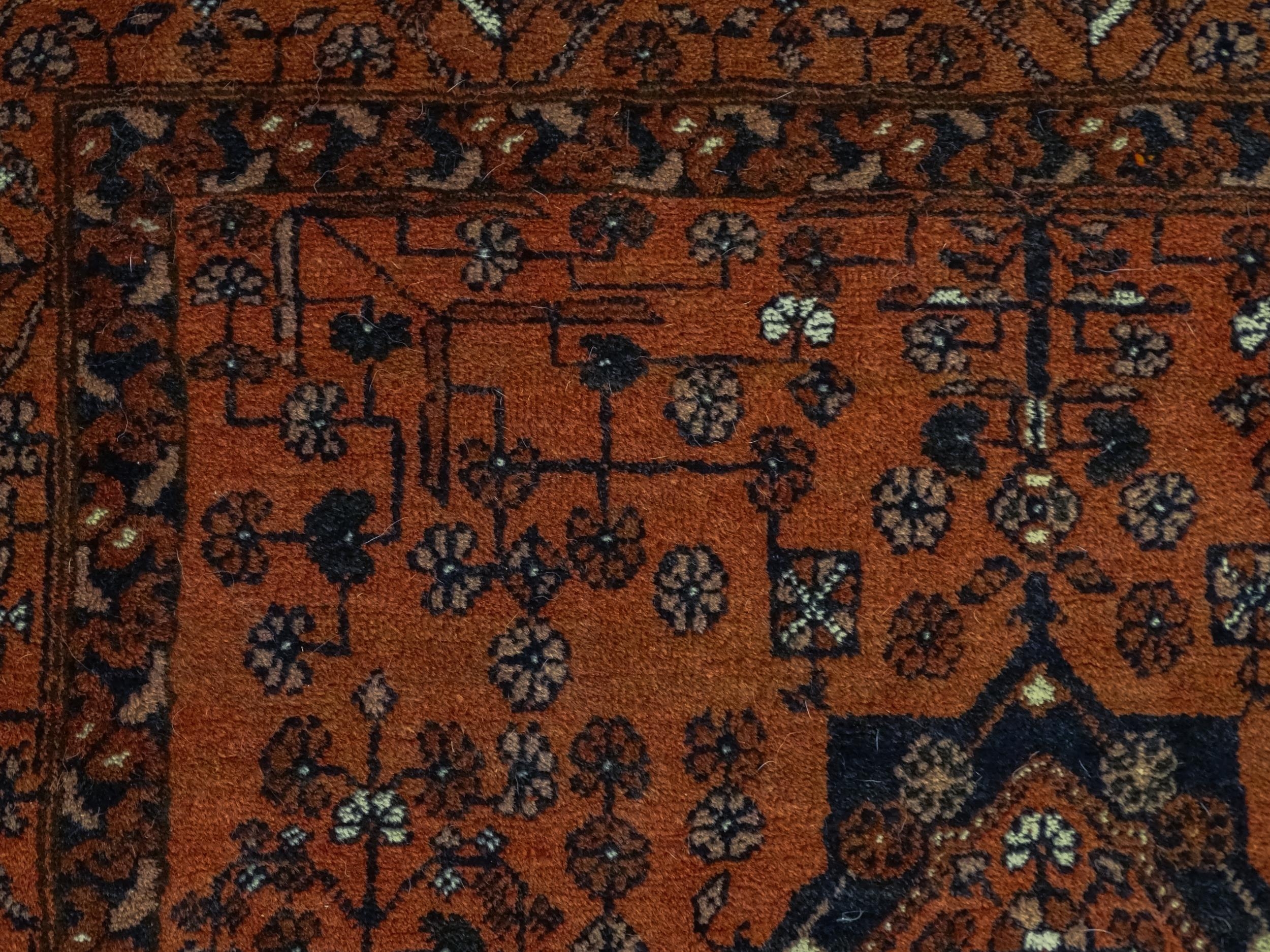 Carpet / Rug: A red ground rug decorated with floral and foliate detail, further repeated to - Image 5 of 8