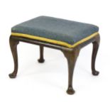 An 18thC walnut stool with a rectangular upholstered top above four cabriole legs terminating in pad