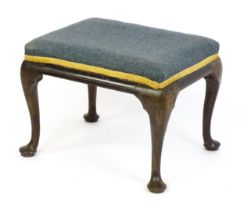 An 18thC walnut stool with a rectangular upholstered top above four cabriole legs terminating in pad