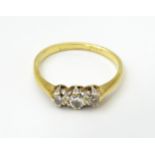 A gold ring set with a trio of diamonds in a platinum setting. Ring size approx. M Please Note -