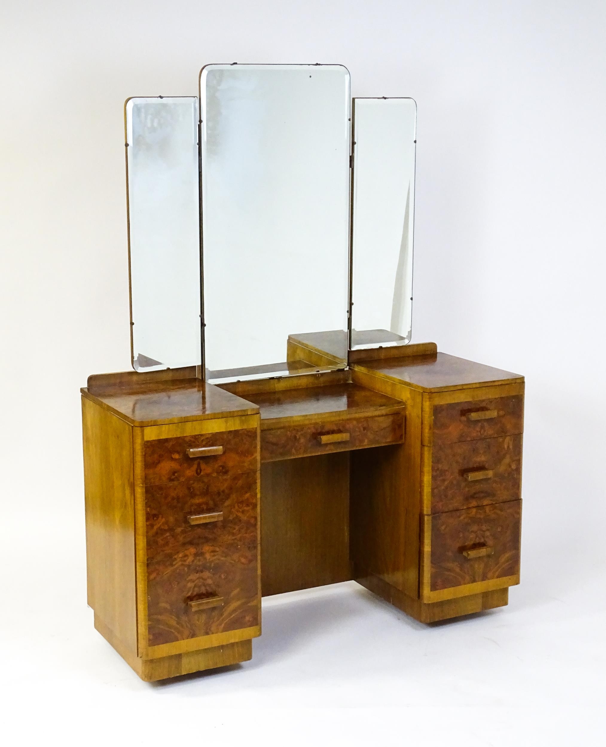 A mid 20thC Art Deco style burr walnut veneered dressing table with a triptych mirror above a