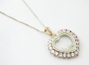 A silver chain with heart shaped locket pendant set with white stones with further white stones
