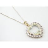 A silver chain with heart shaped locket pendant set with white stones with further white stones