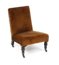 A 19thC nursing chair with a sprung seat raised on turned tapering front legs terminating in