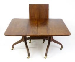 A Georgian mahogany double pedestal dining table raised on reeded legs terminating in brass caps and