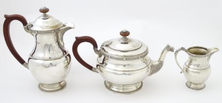 A three piece silver tea set comprising teapot, hot water pot and cream jug, with Celtic style