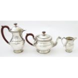 A three piece silver tea set comprising teapot, hot water pot and cream jug, with Celtic style