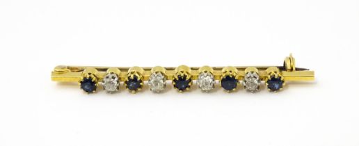 A gold bar brooch with platinum set diamonds, and blue stones. Approx. 2" long Please Note - we do