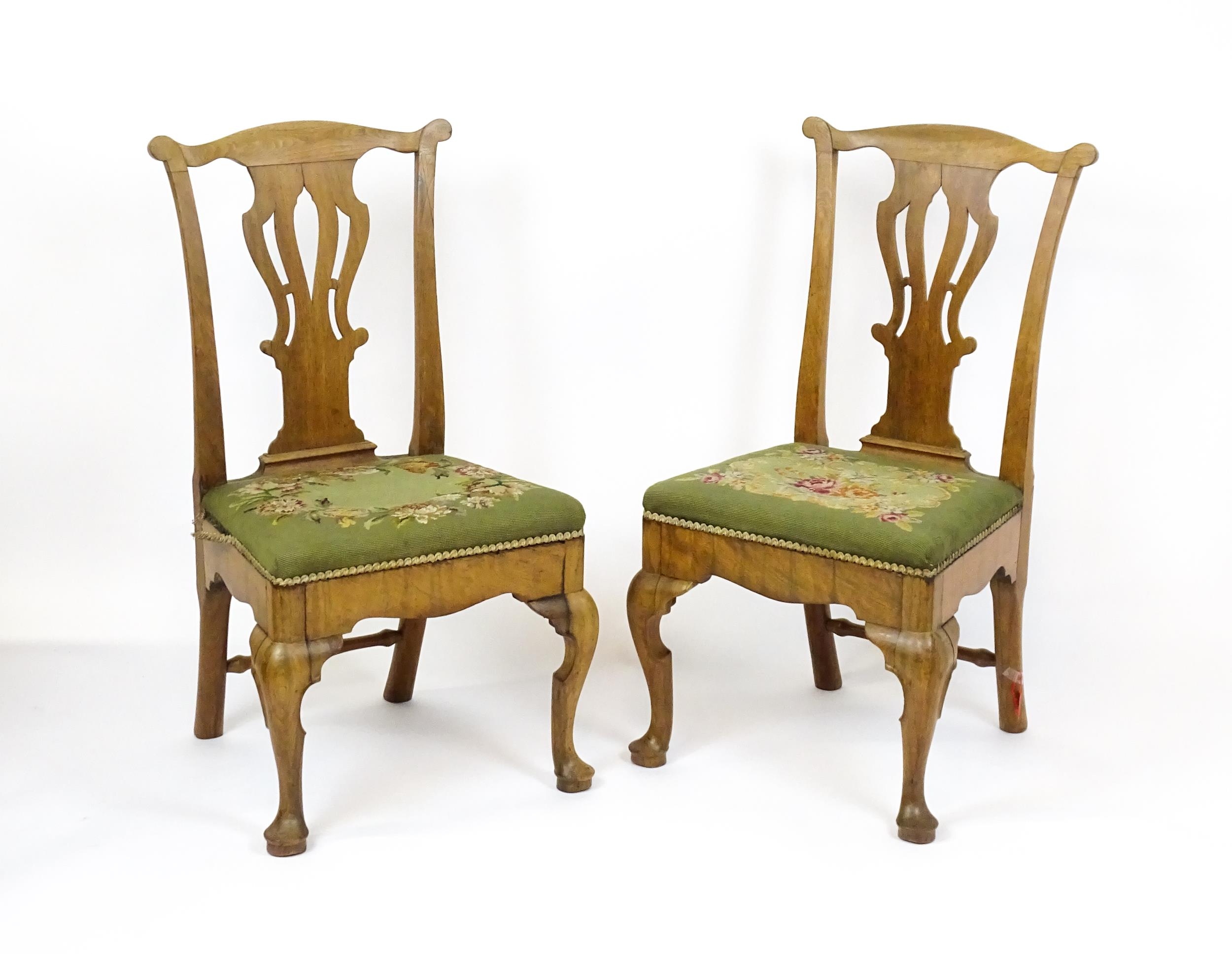 A pair of George II walnut side chairs with shaped top rails above pierced splats and raised on