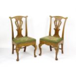 A pair of George II walnut side chairs with shaped top rails above pierced splats and raised on