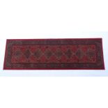 Carpet / Rug : A red ground runner with repeating motifs to centre, bordered by geometric banding.