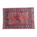 Carpet / Rug : A Pakistan wool red ground rug decorated with repeating geometric motifs with further
