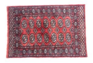 Carpet / Rug : A Pakistan wool red ground rug decorated with repeating geometric motifs with further