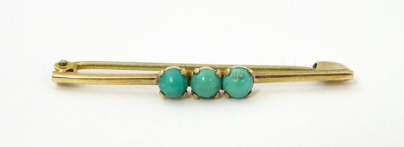 A 9ct gold bar brooch set with three turquoise cabochon. Approx. 1 3/4" wide Please Note - we do not