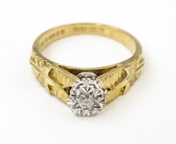 A 9ct gold ring set with central illusion set diamond with star detail to shoulders. Ring size