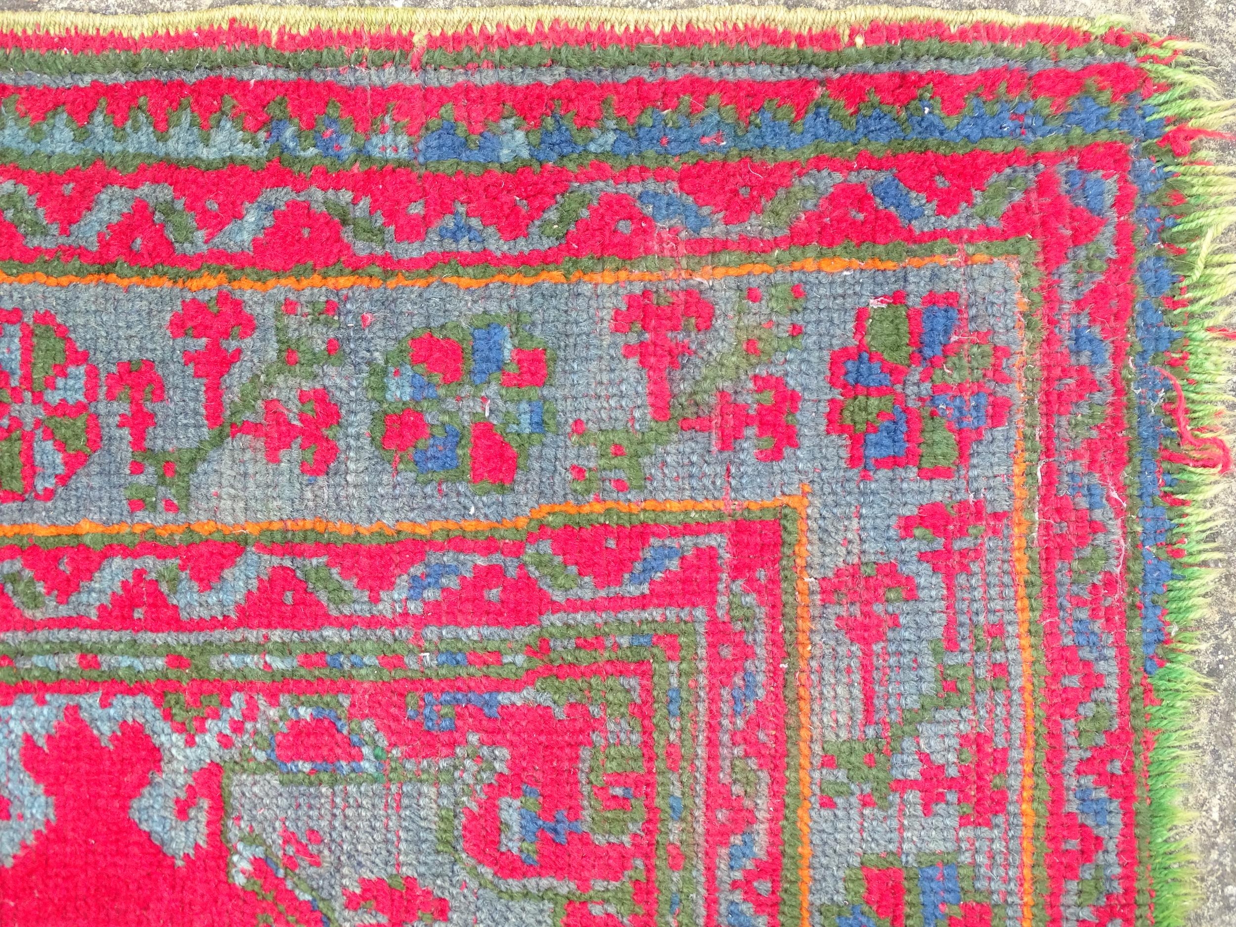 Carpet / Rug : A red ground rug decorated with floral, foliate and geometric detail worked in blue - Image 3 of 7