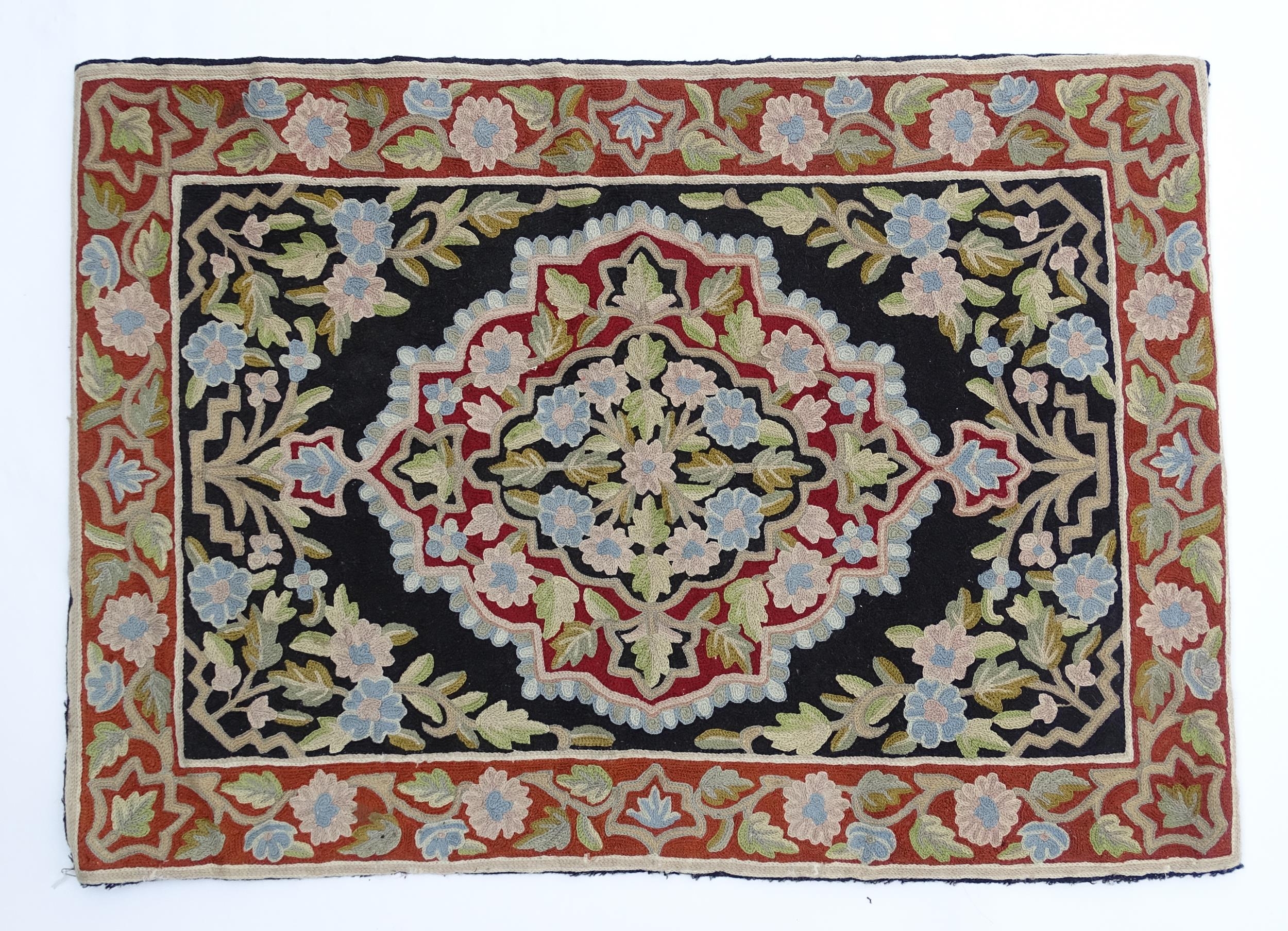 Carpet / Rug : A black and red ground rug with floral and foliate detail. Approx. 35" x 24 1/2"