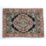 Carpet / Rug : A black and red ground rug with floral and foliate detail. Approx. 35" x 24 1/2"